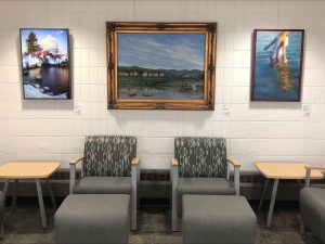 Three pieces of art displayed behind two chairs at Rochester International Airport.