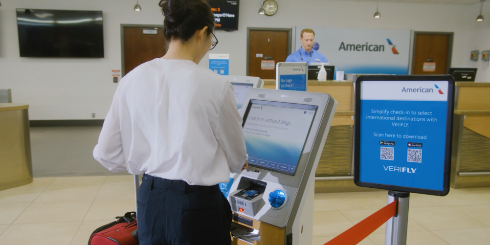 A passenger uses a kiosk to check in as an agent from American Airlines works in the background at Rochester International Airport.